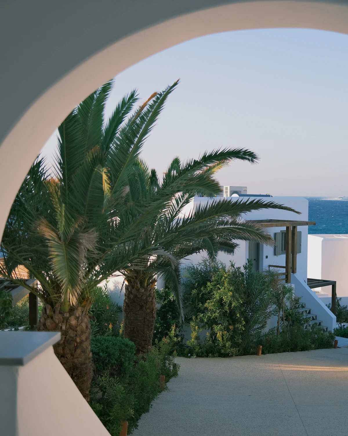 A whitewashed arch framing palms and the sea at Villa Sereno.
