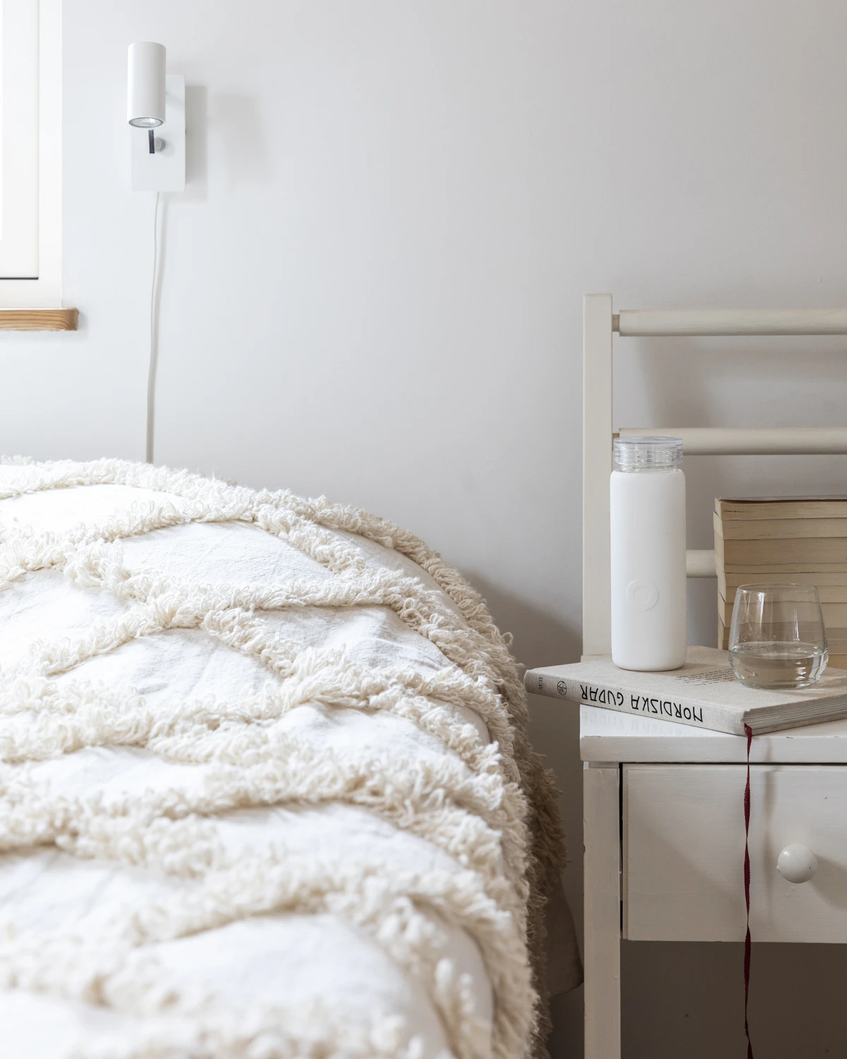 A bedroom with white linen and light from a small window.